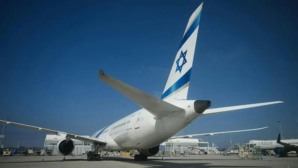 An El Al airplane is parked at an airport gate under a clear blue sky.