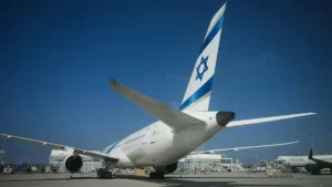An El Al airplane is parked at an airport gate under a clear blue sky.