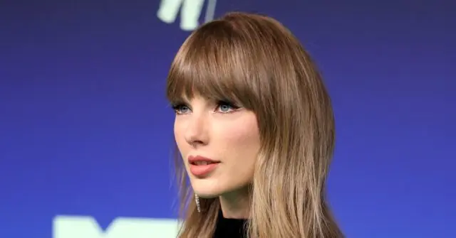 The image shows a person with long blonde hair and bangs, wearing a black top, against a blue background with a logo partially visible.