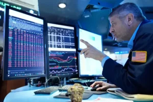A trader is analyzing financial data on multiple computer screens in a modern trading environment.