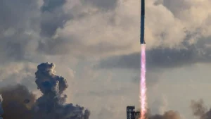 A rocket launches into the sky, leaving a trail of smoke and fire as it ascends against a backdrop of clouds.