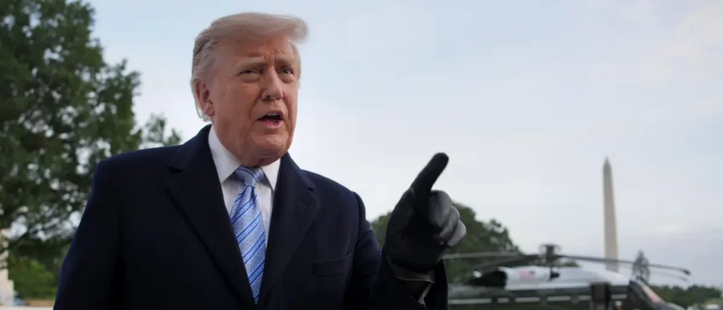The image shows a person in a suit and tie, gesturing with their right hand, with the Washington Monument visible in the background.