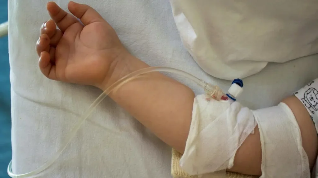 A child's arm is shown with an IV line attached, indicating medical treatment.