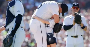 A baseball player is seen hugging a young fan during a game, with other players and a crowd in the background.