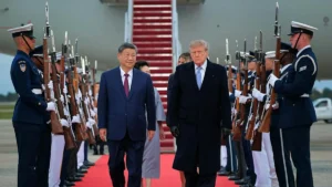 The image shows a formal arrival ceremony with two leaders walking down a red carpet flanked by uniformed guards holding rifles.