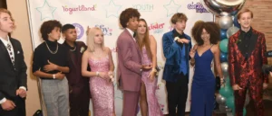 A group of young people dressed in formal attire pose for a photo at a formal event.