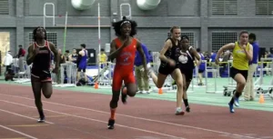 Athletes compete in a sprint race on an indoor track.