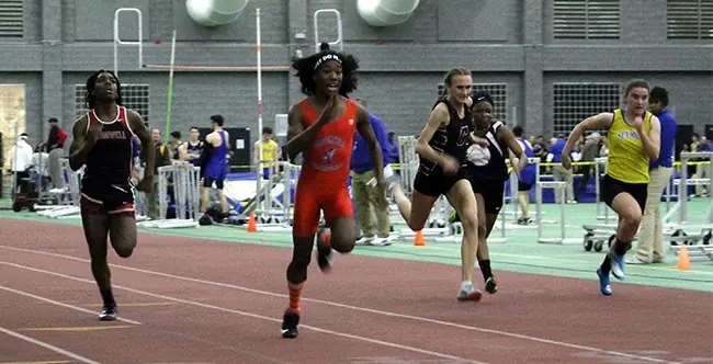 Athletes compete in a sprint race on an indoor track.
