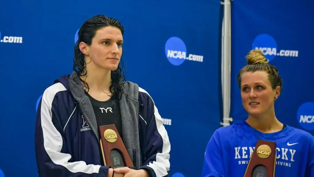 Two female athletes hold NCAA awards at a press conference.