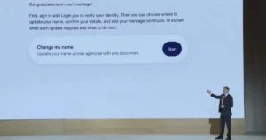 The image shows a person presenting on a stage with a screen displaying instructions for updating name and details after marriage, using Login.gov.
