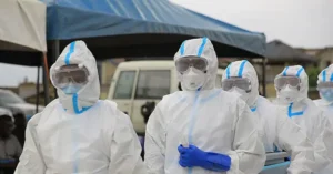 A group of healthcare workers in full protective gear stands together, ready to assist during a medical emergency.