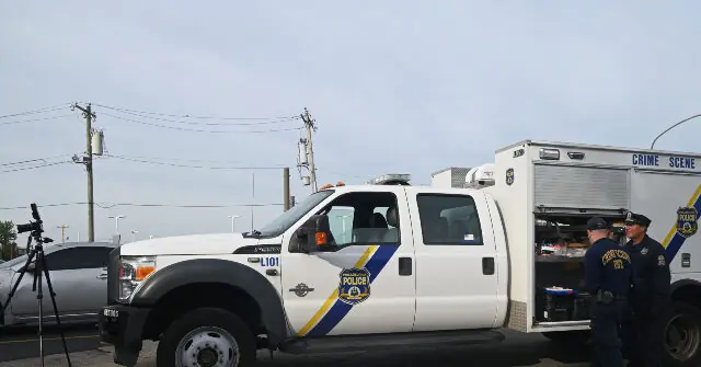 A police truck and a crime scene unit are parked at a location, with officers standing nearby, suggesting an ongoing investigation or incident.