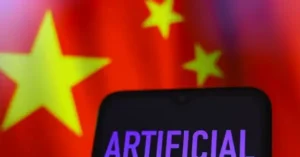 The image shows a smartphone screen with the word "ARTIFICIAL" displayed, set against a blurred background of the Chinese flag.