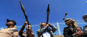A group of individuals are holding weapons and appear to be in a tense or confrontational situation.