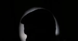 The image shows a silhouette of a person with a halo-like light effect behind their head, creating a dramatic and symbolic visual.