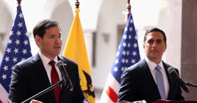 Two men in suits stand at podiums with American and another flag behind them, likely during a formal press event or announcement.