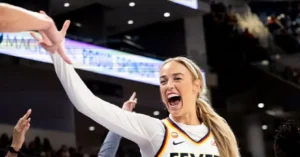 A basketball player celebrates enthusiastically with a high-five gesture during a game.