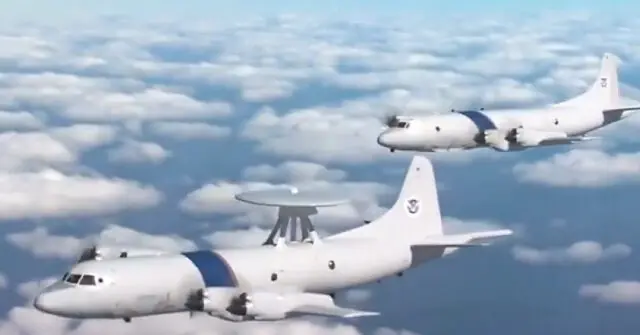 Two U.S. Coast Guard P-3 Orion aircraft are flying in formation above the clouds.