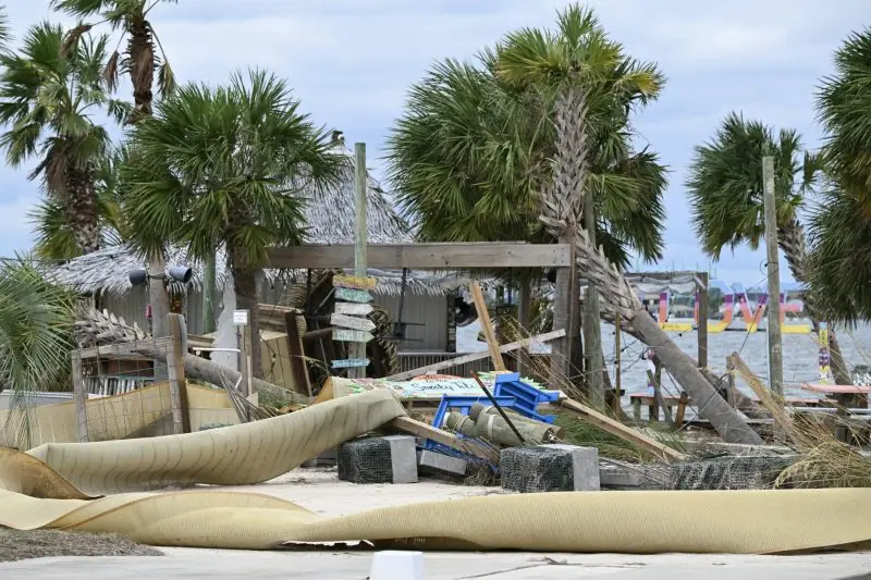 The image shows the aftermath of a storm, with debris and damaged structures near a beachside area.