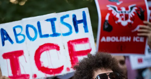 The photo shows a protest with signs advocating for the abolition of ICE (Immigration and Customs Enforcement).