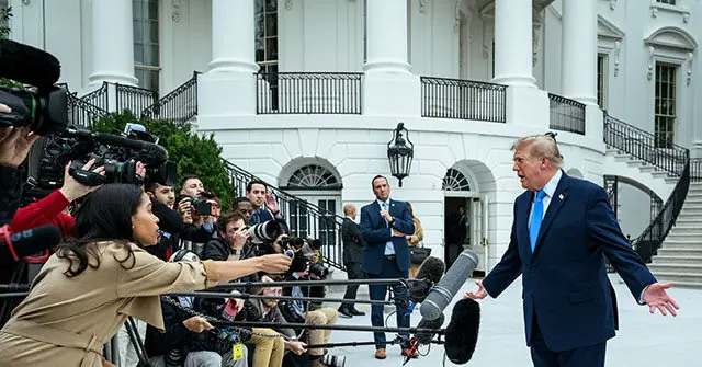 A political figure addresses the media in front of the White House, surrounded by reporters and cameras.