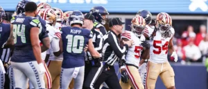 A football referee attempts to separate players from the Seattle Seahawks and the San Francisco 49ers during a game.