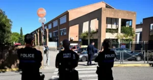 Police officers are seen standing near a building with a "SAUF VEHICULES AUTORISES" sign, indicating restricted access for unauthorized vehicles.