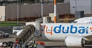 A FlyDubai aircraft is parked at an airport gate with passengers boarding through a jet bridge.