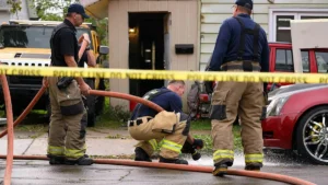 Firefighters are working to connect a hose at the scene of a house fire.