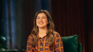 A woman in a colorful striped shirt is smiling while sitting on a green couch.