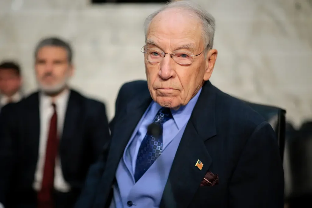 The image shows a man in formal attire, likely participating in a formal or official event, as indicated by the American flag pin on his lapel.