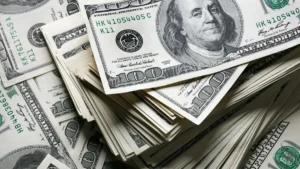 The image shows a pile of one hundred-dollar bills, symbolizing wealth or financial transactions.