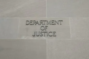 The image shows a sign for the Department of Justice on a stone wall.