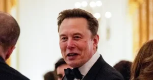 The image shows a man in formal attire, including a bow tie, engaged in conversation at what appears to be a formal event.
