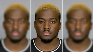 The image appears to be a mugshot of a person with a distinctive hairstyle and facial features.