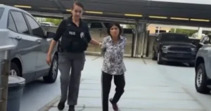 A police officer is escorting a person through a parking garage.