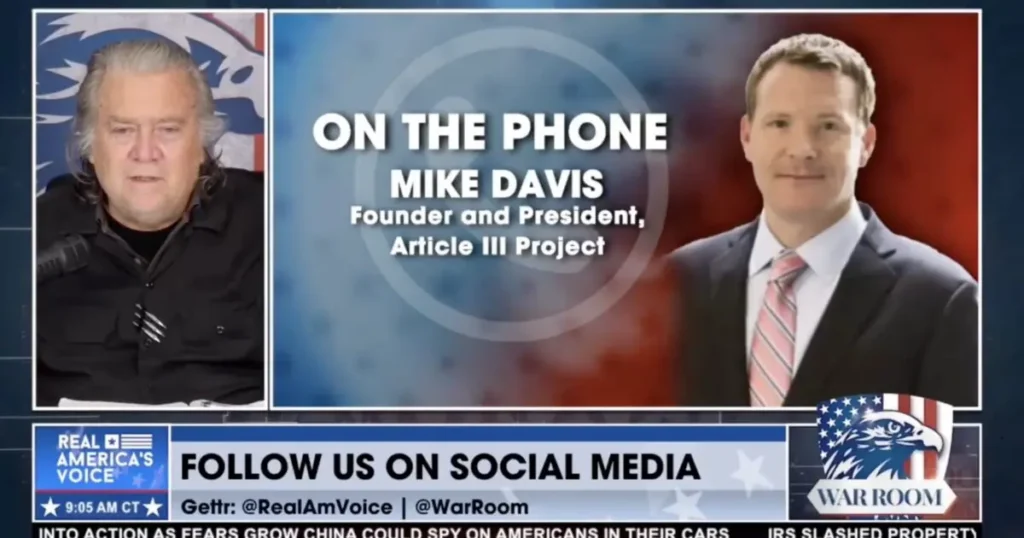 The image shows a news broadcast featuring Mike Davis, the founder and president of the Article III Project, on the phone, with a patriotic background and social media handles displayed.