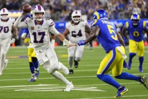 A football player in a white uniform with the number 17 is preparing to throw the ball during a game against a team in blue and yellow uniforms.