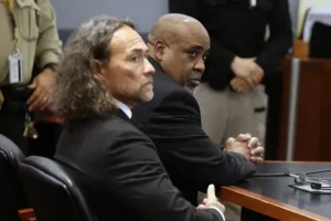 Two men are seated in a courtroom, appearing attentive and serious during a legal proceeding.