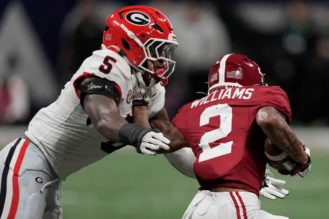A Georgia Bulldogs player tackles an Alabama Crimson Tide player during a football game.