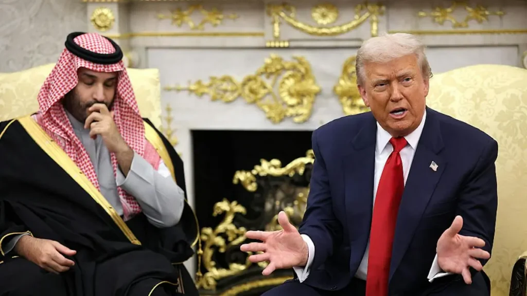 The image shows two individuals engaged in a discussion in a formal setting with ornate decor.