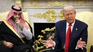 The image shows two individuals engaged in a discussion in a formal setting with ornate decor.