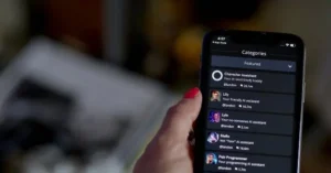 The image shows a hand holding a smartphone displaying a list of AI assistant categories, including "Character Assistant," "Lily," "Lyle," "Stella," and "Pair Programmer."