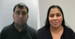 The image shows two individuals, a man and a woman, standing side by side against a plain background.