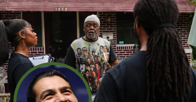 A man in a group photo t-shirt is speaking to two women in front of a brick building.