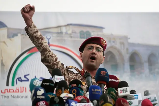 A military officer raises his fist in a gesture of solidarity or defiance while addressing a press conference.