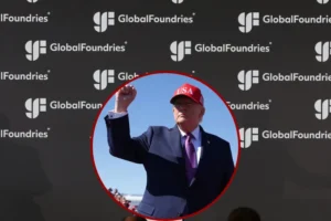 The image shows a person wearing a "USA" hat and a suit, raising their fist in a gesture, with a backdrop featuring the "GlobalFoundries" logo.