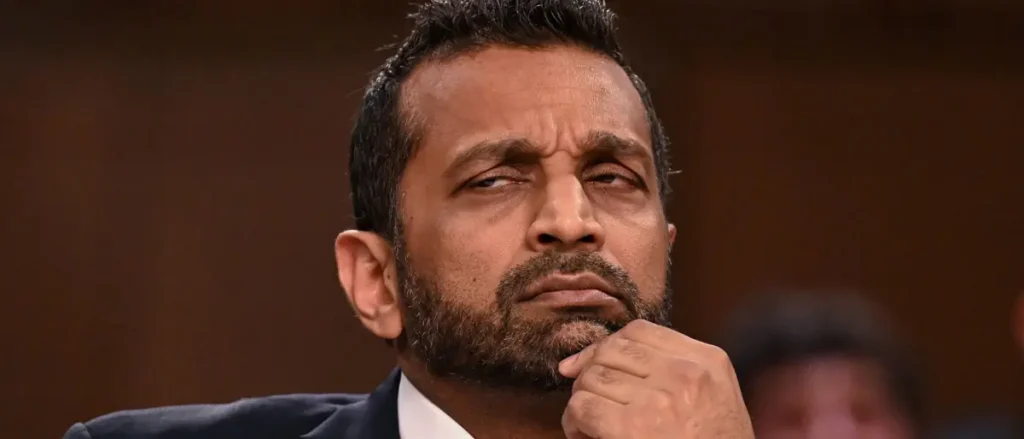 The image shows a man in a suit with his hand on his chin, appearing thoughtful or contemplative.
