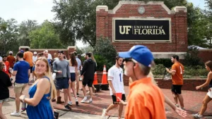 The photo captures a lively scene at the University of Florida, with students and visitors gathered near the entrance sign.