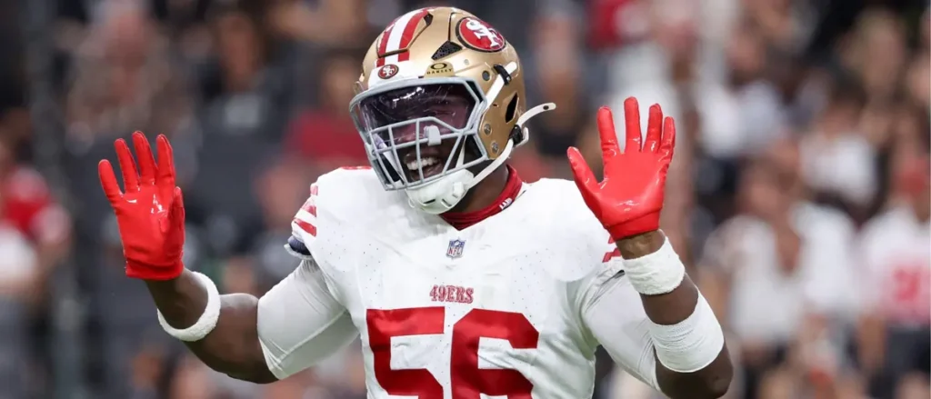 A San Francisco 49ers player celebrates with his hands raised during a game.